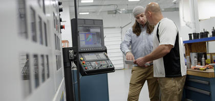 Podmore and Jurick reviewing a setup sheet for the multi-task machine