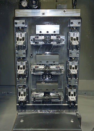 This single-face tombstone holds 12 parts in process, and finishes 6 in each cycle. The 6 along the sides undergo the first operation, which also machines the parts through windows in back, while the 6 parts in the center are finished with a second operation.