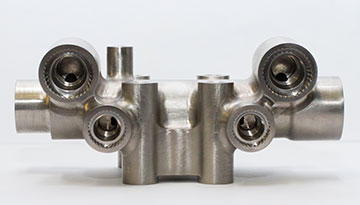Part orientation, such as that required to machine the angled .060” wide slotted orifices inside the lower ports of this titanium manifold, is enabled with special fixtures and 5-axis programming for the 4-axis mill, which Jesse Alvarado does with GibbsCAM.