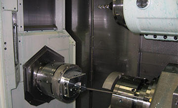 Machining the grip body requires no turning work, but the Mazak Integrex, as programmed with GibbsCAM, enables machining the entire part in a single set-up. It begins as round stock, as shown here, in the main spindle, ready for transfer to the subspindle for completion. Machining on a multi-task machine, saves 6 hours of set-up and cuts machining time from 111 minutes per part, to 43 minutes.