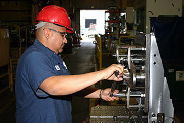 Luis Guerrero, horizontal mill set-up machinist, mounts a rod hook bail casting for machining. Mounting fixtures accommodate machining from as many directions as possible, eliminating setups.