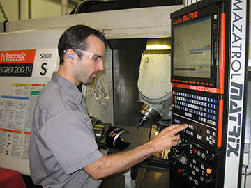 Nathan Neels makes an adjustment on a control for the 7 axis Mazak Integrex machine.