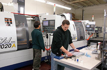 Joshua Jordan, David Jordan’s son, checks a part for precision. Background is Tien Kiet at a YCM 1020 A VMC. (Two shown.)