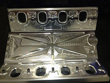 Manifold valley and flanges machined from billet show the pattern VoluMill creates when it generates the most efficient toolpath motion for running at maximum RPM and feed rate, while machining the 1/2” deep pockets in a single pass. Switzer leaves the machined finish to demonstrate part quality and beauty.
