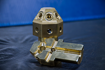Nash instructors cut a nozzle in half to show part complexity. Note the reverse conical shape (dovetail) within upper orifices, which required 5-axis milling, easily accommodated with a tilting rotary trunnion.
