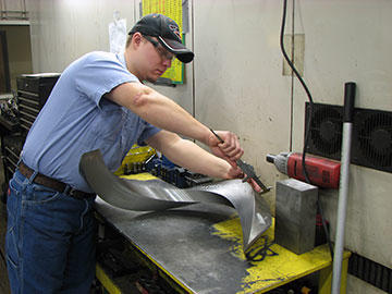 Machinist Tim Staver checks the cross section of an auger flighting. This part is machined with the cutting tool offset from the radial center to achieve a right-angle cross section, as opposed to the keystone shape that would result from on-center machining.