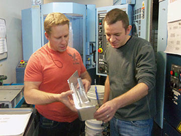 Shop team lead John Perry, left and Steve Glover, CNC programmer, examining a machined part