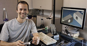 Rob Pleas holds a machined tripod-head bracket, during inspection, displaying solid models of brackets in GibbsCAM, which directly opens product and part designs he creates with SolidWorks.